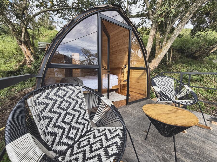 Fachada en arco de Alma con sillas tejidas y mesa de madera en la terraza